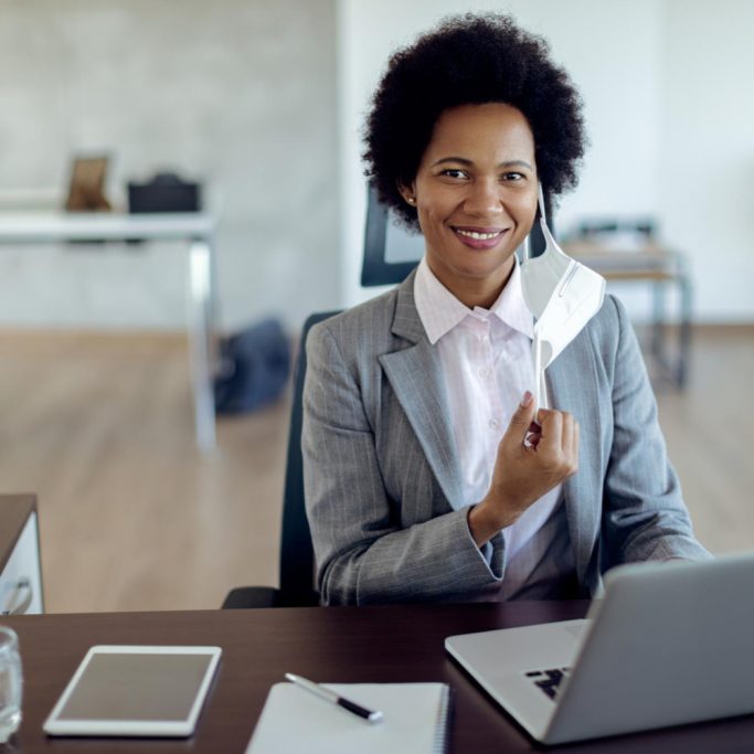happy-black-businesswoman-with-protective-face-mask-working-office
