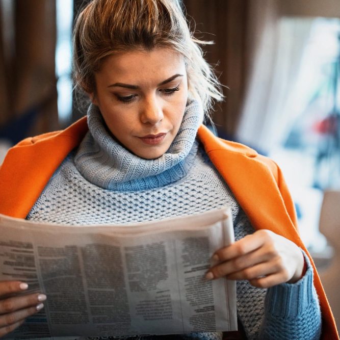 beautiful-female-entrepreneur-reading-newspaper-while-relaxing-cafe