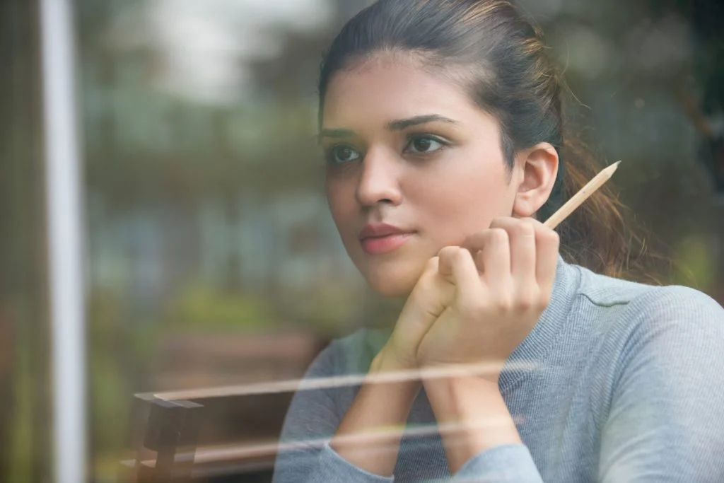 thoughtful-student-holding-pencil-glass