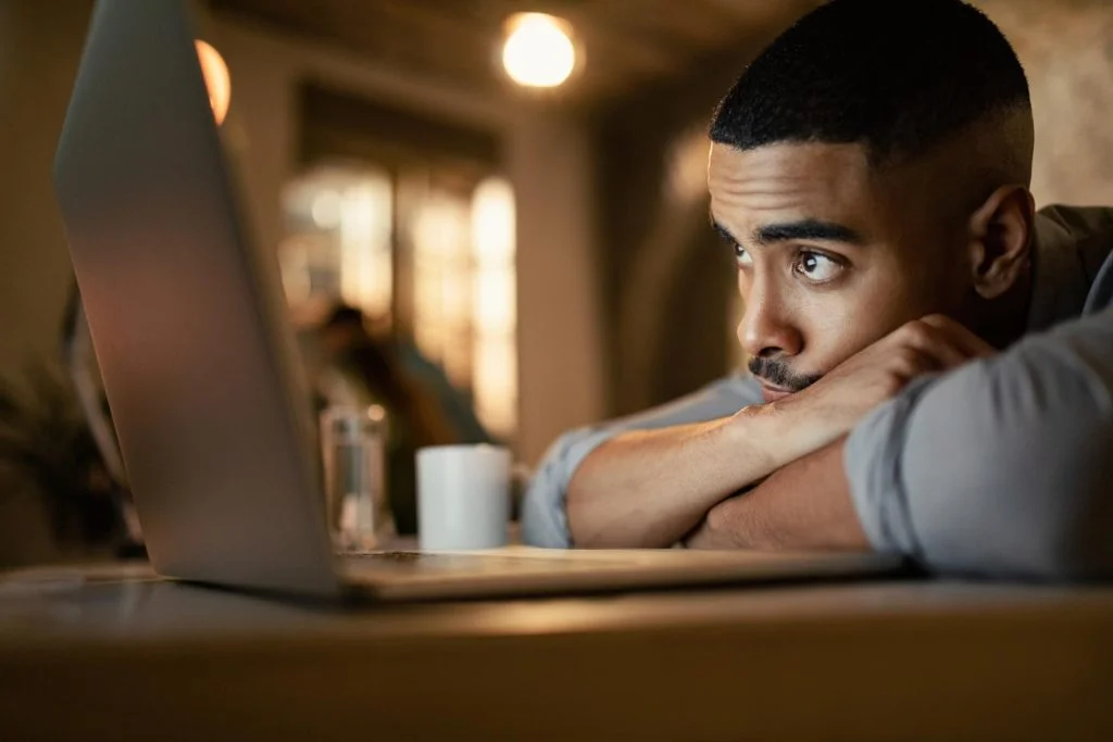 young-black-businessman-leaning-his-desk-while-working-computer-night